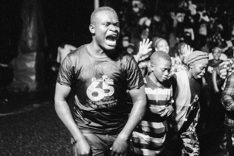 © Jeff Tidwell - A group of young adults running and shouting during a rainstorm