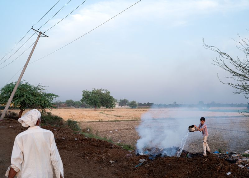 © Giovanni De Mojana - Near the Pakistan- India border, in Lahore, a boy extinguishes a controlled fire used to burn waste and brush.