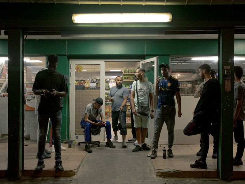 © William Keo - FRANCE. Stains. 2023. Young people hang out outside a grocery store during the summer.