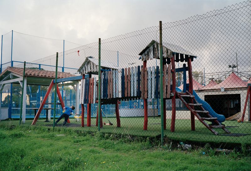 © Marco Waldis - A kid in a local playground protected by a fence.