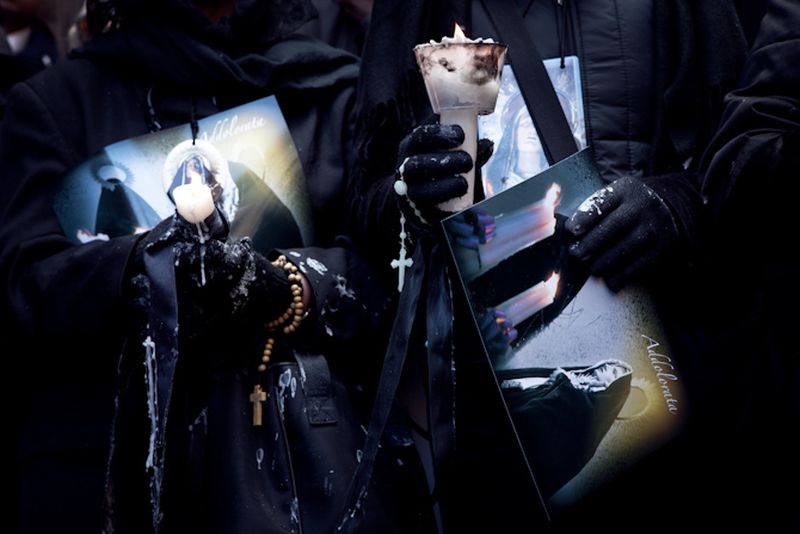 © Antonio Sansica - Two ladies march along the “Lady of Sorrow” holding candles and postcards of the Virgin Mary