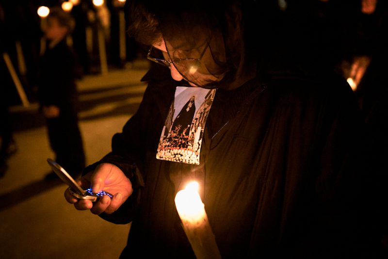 © Antonio Sansica - A woman, alongside the “Lady of Sorrow”, check her phone during the procession.