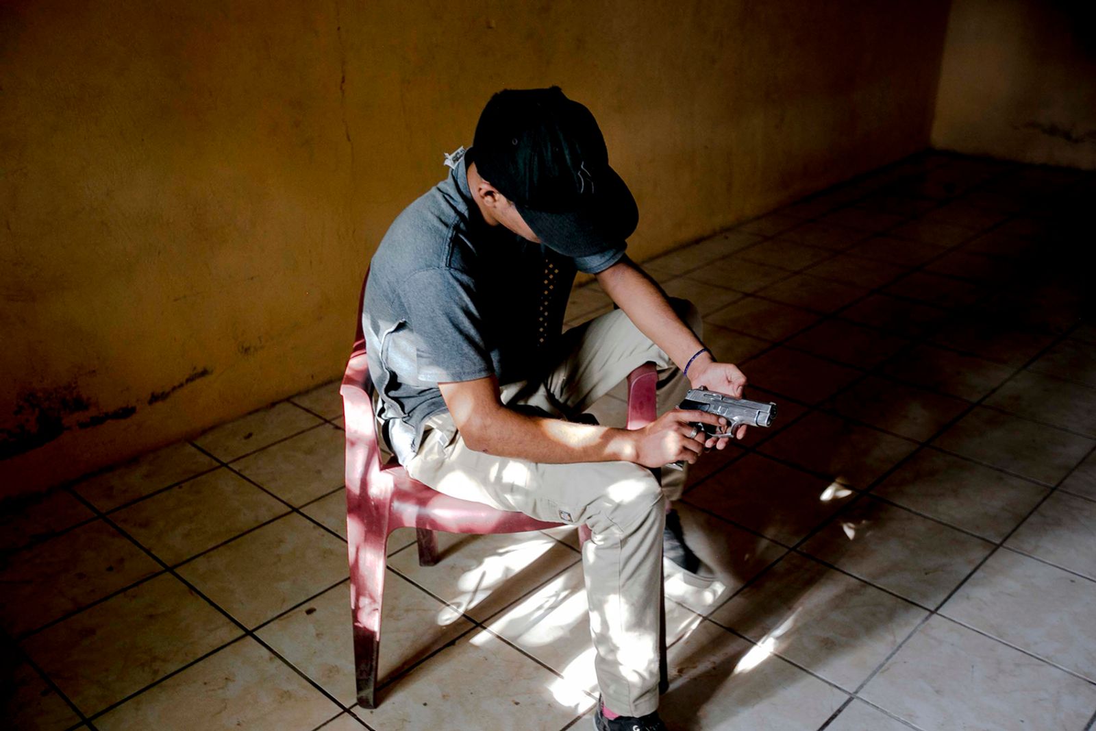 © Fred Ramos - A 15-year-old gang member with a gun in a house in La Paz, El Salvador, July 2016. Fred Ramos