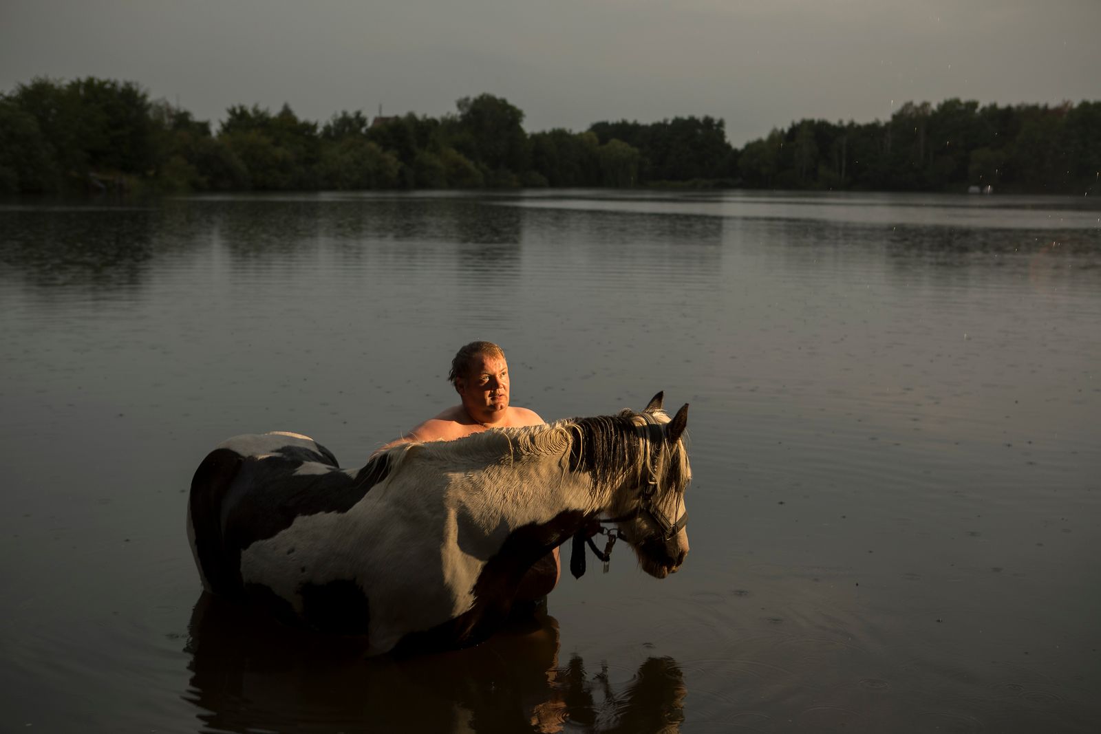 © Lara Wilde - A man taking a swim in the rain with his horse. He saved it from the butcher.