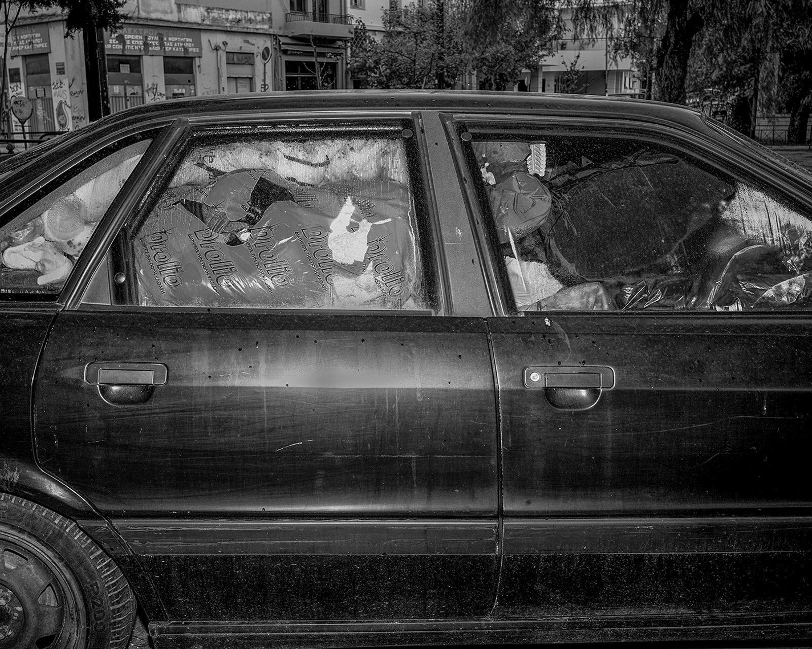 © Angelos Tzortzinis - Clothes are packed in a car which serves as shelter for a homeless man under a bridge in a ghetto area in Athens.