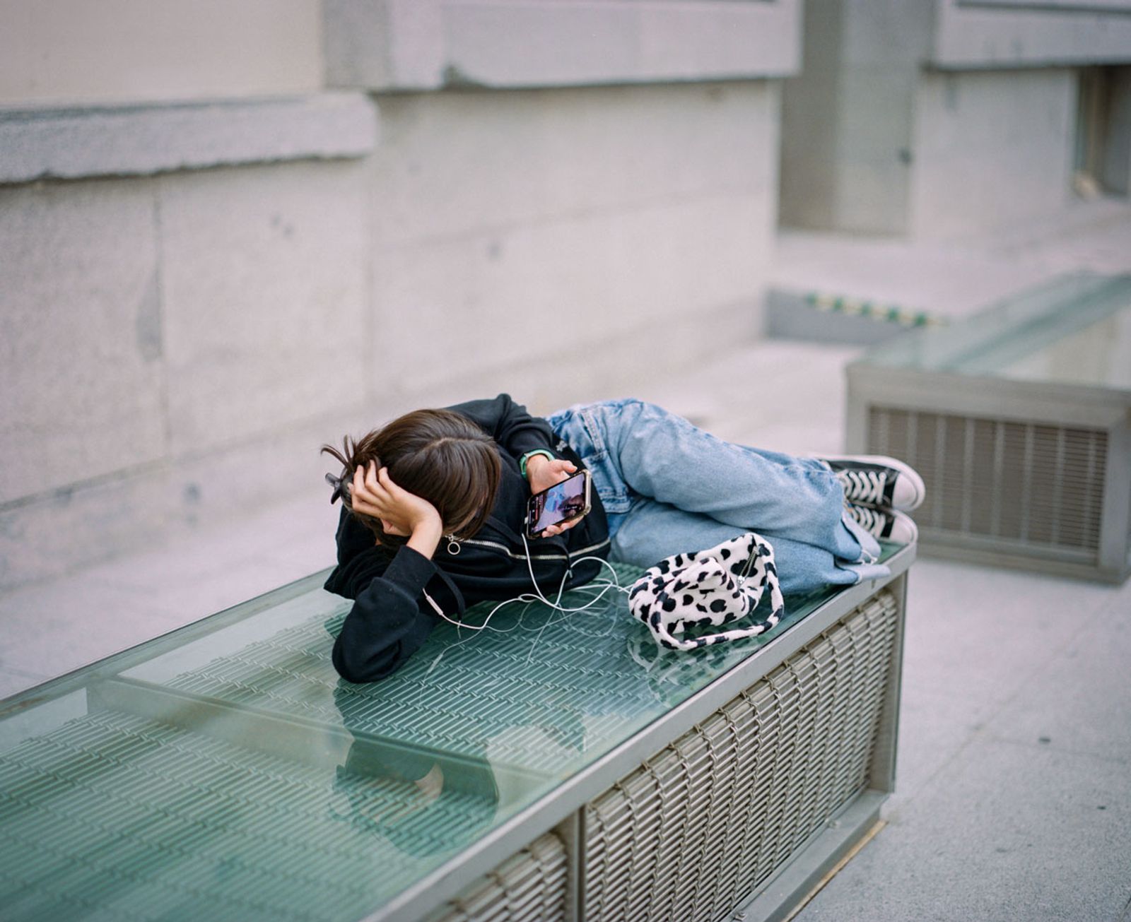 © Juan de la Quintana - A bored young woman, lying on a bench in the fetal position.