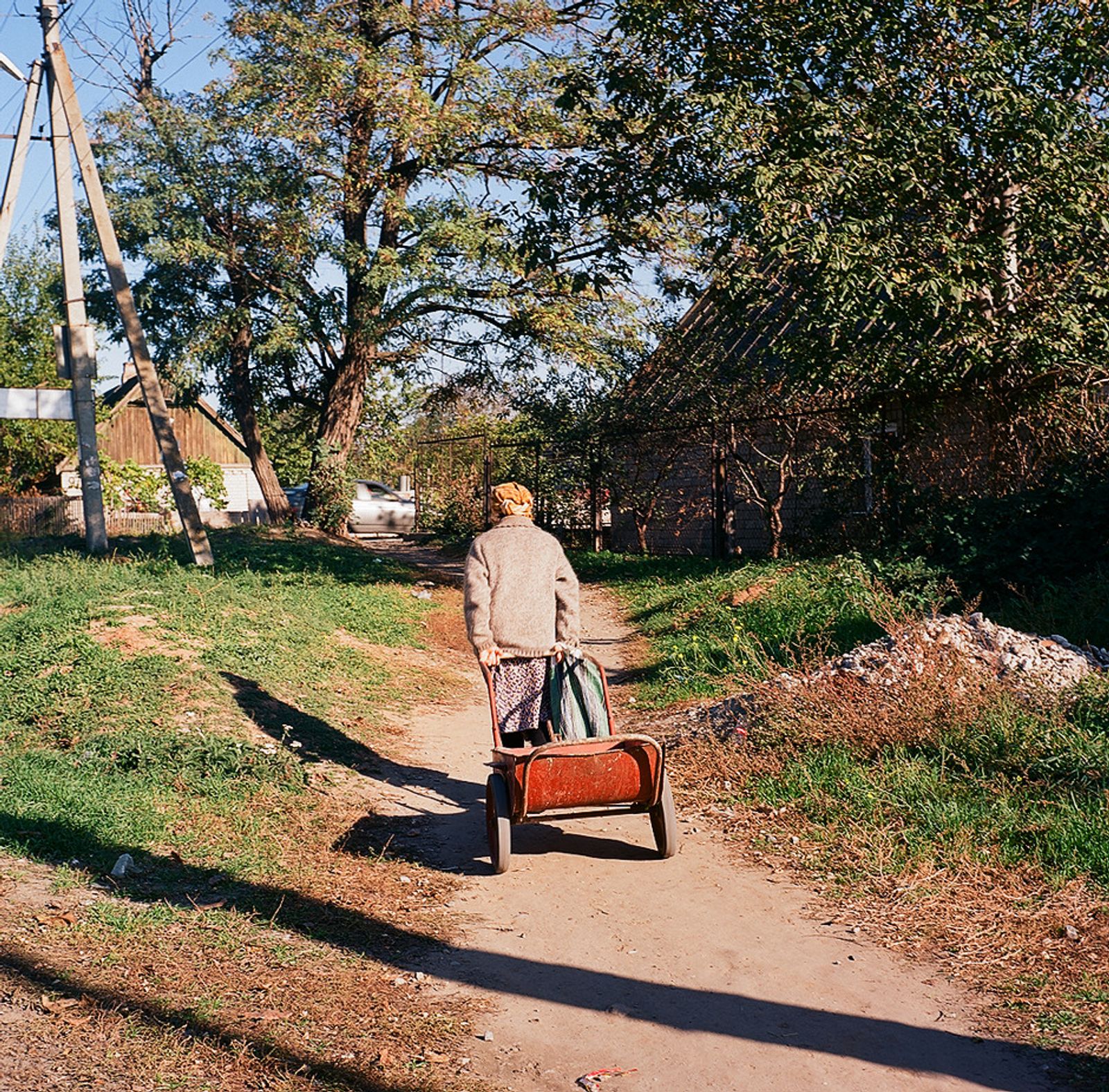 © Natalia Shlyakhovaya - An old woman draging her small cart with cement. Kushugum, Zaporizhia Oblast, Ukraine.