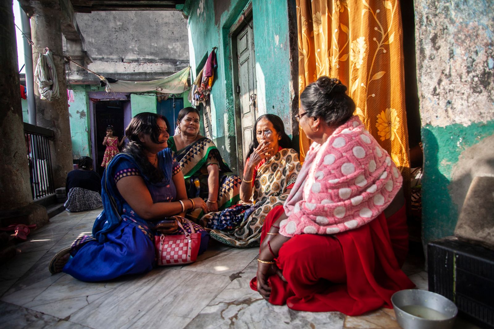© Chiara Ferronato - A few sex workers talk and relax outside their rooms in one of Sonagachi brothels.