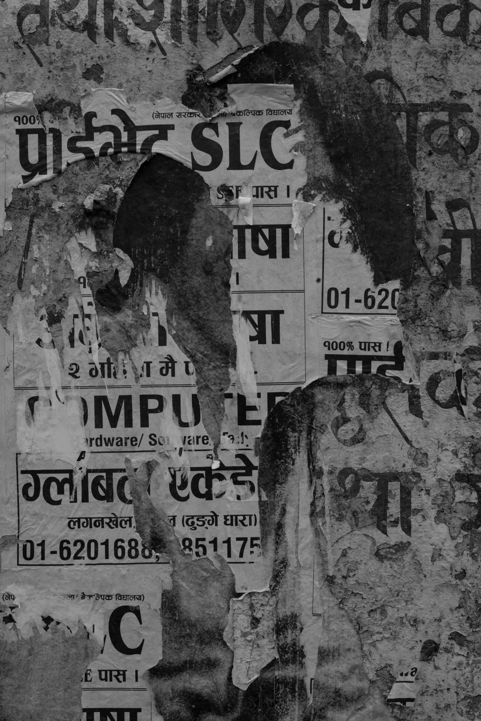 © Stephen Dock - A ragged poster for computing classes stuck on a wall hides a portrait, in Patan, Nepal.