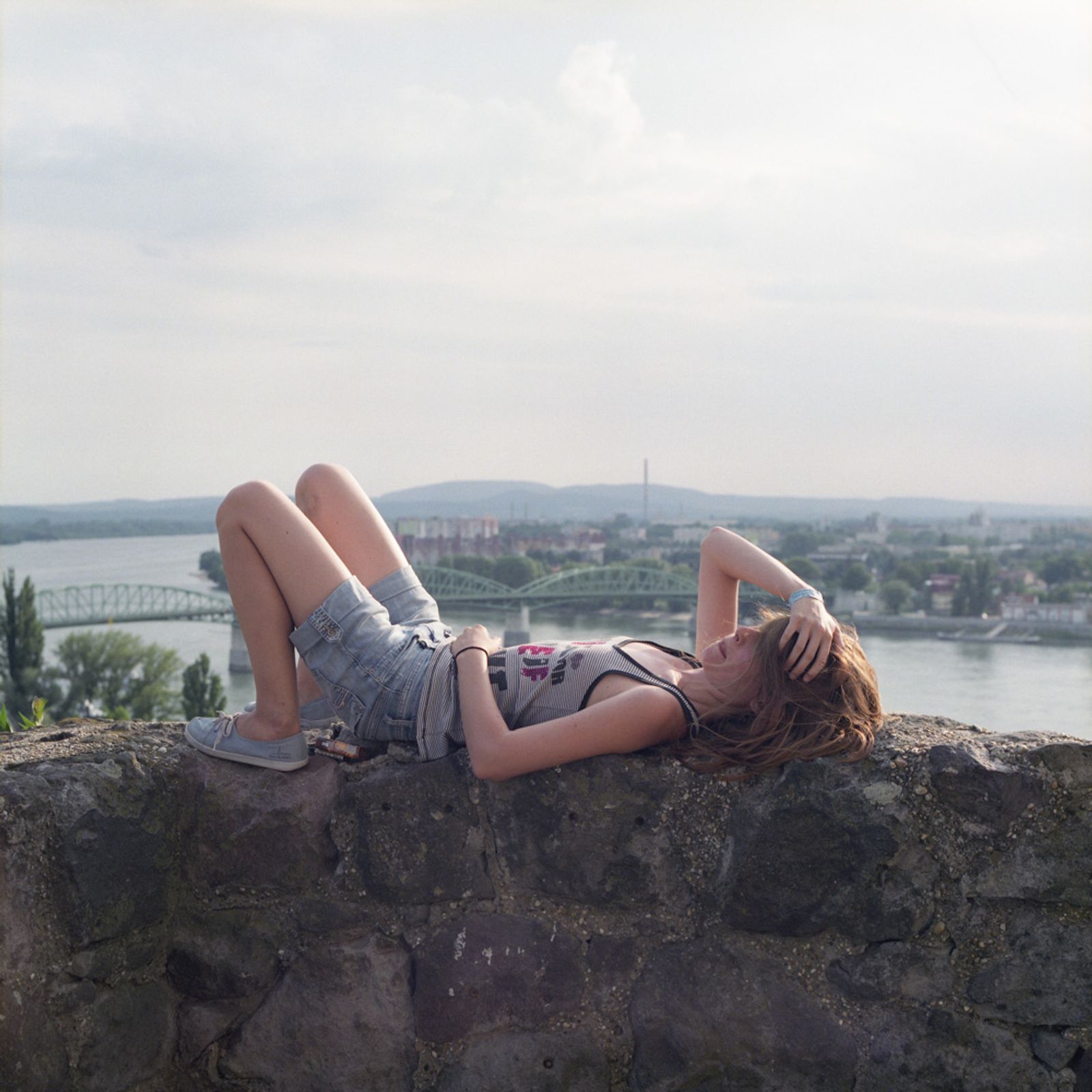 © Chiara Fossati - A young girl in Esztergom sunbathes while waiting for some friends at the top of the Castle overlooking the Danube, Hungary.