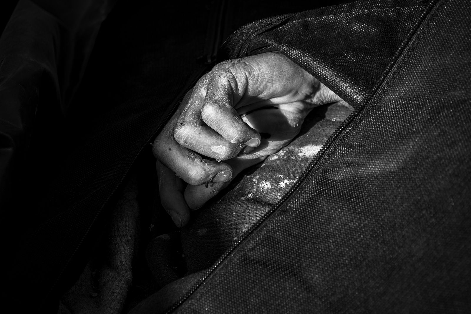 © Zobair Movahhed - A lone hand is visible through a body bag in a dumpster full of the dead bodies of Afghan refugees.