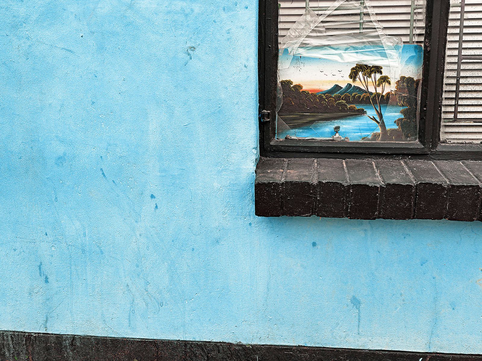 © Graeme Williams - Upington, South Africa. 2011. A cheap painting is used to block a broken window.