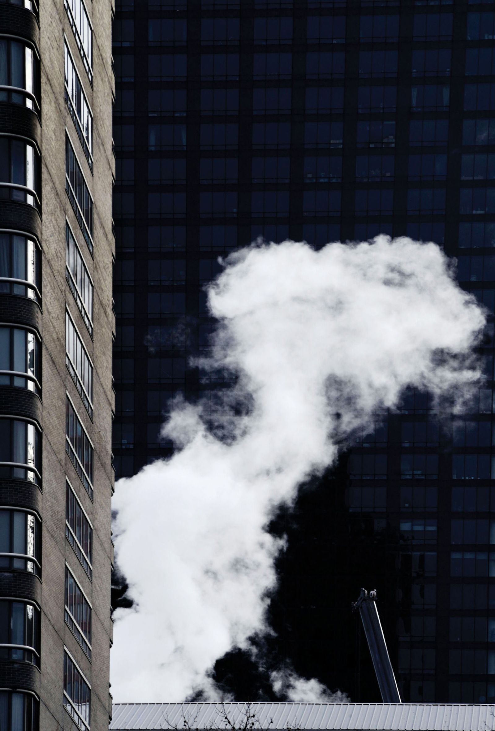 © Graeme Williams - New York, USA. 2016. A steam cloud rises from a block of flats in a densely populated district.
