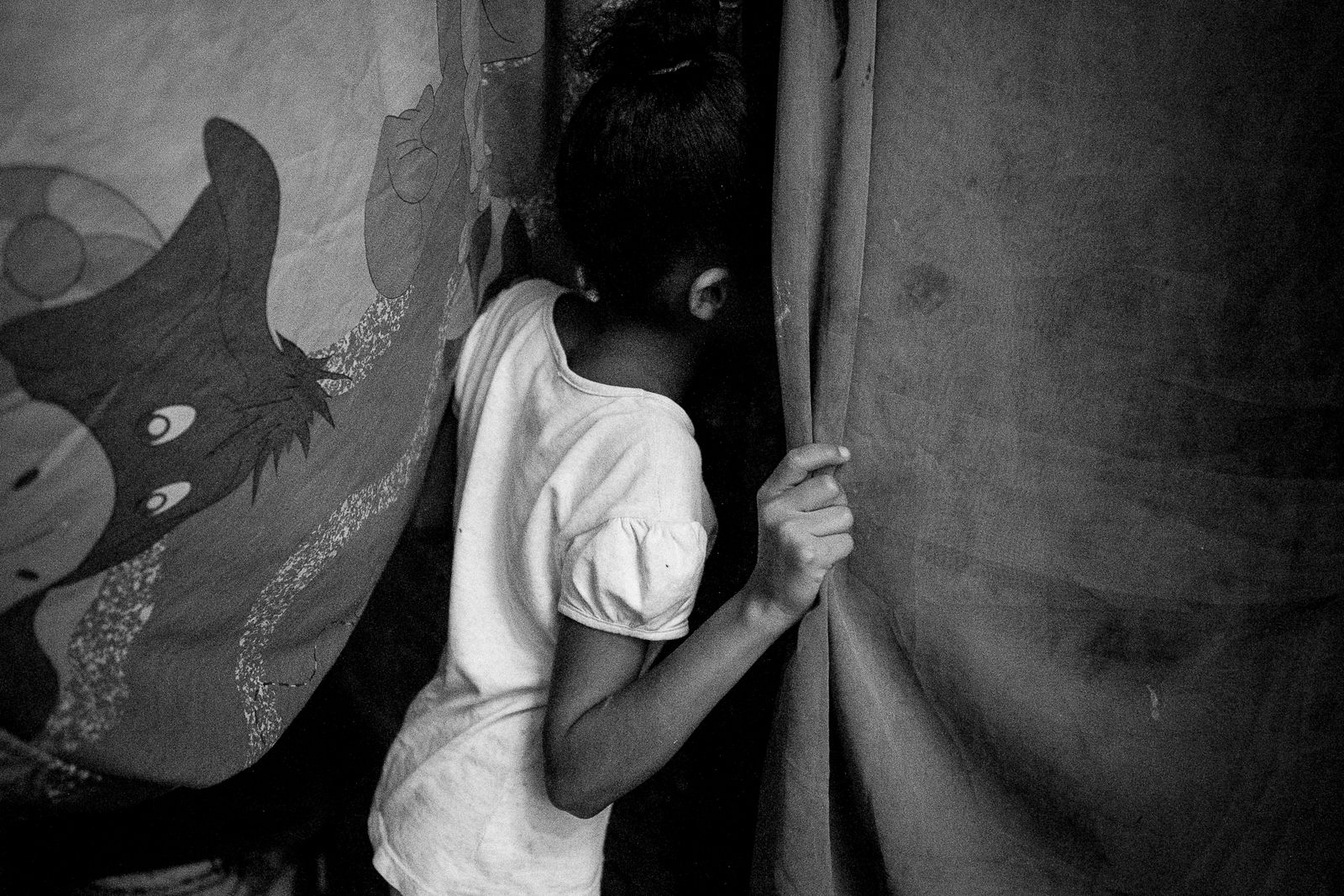 © Fabiola Ferrero - A girl looks inside her house throught the sheets that work as doors in Petare barrio, Caracas.