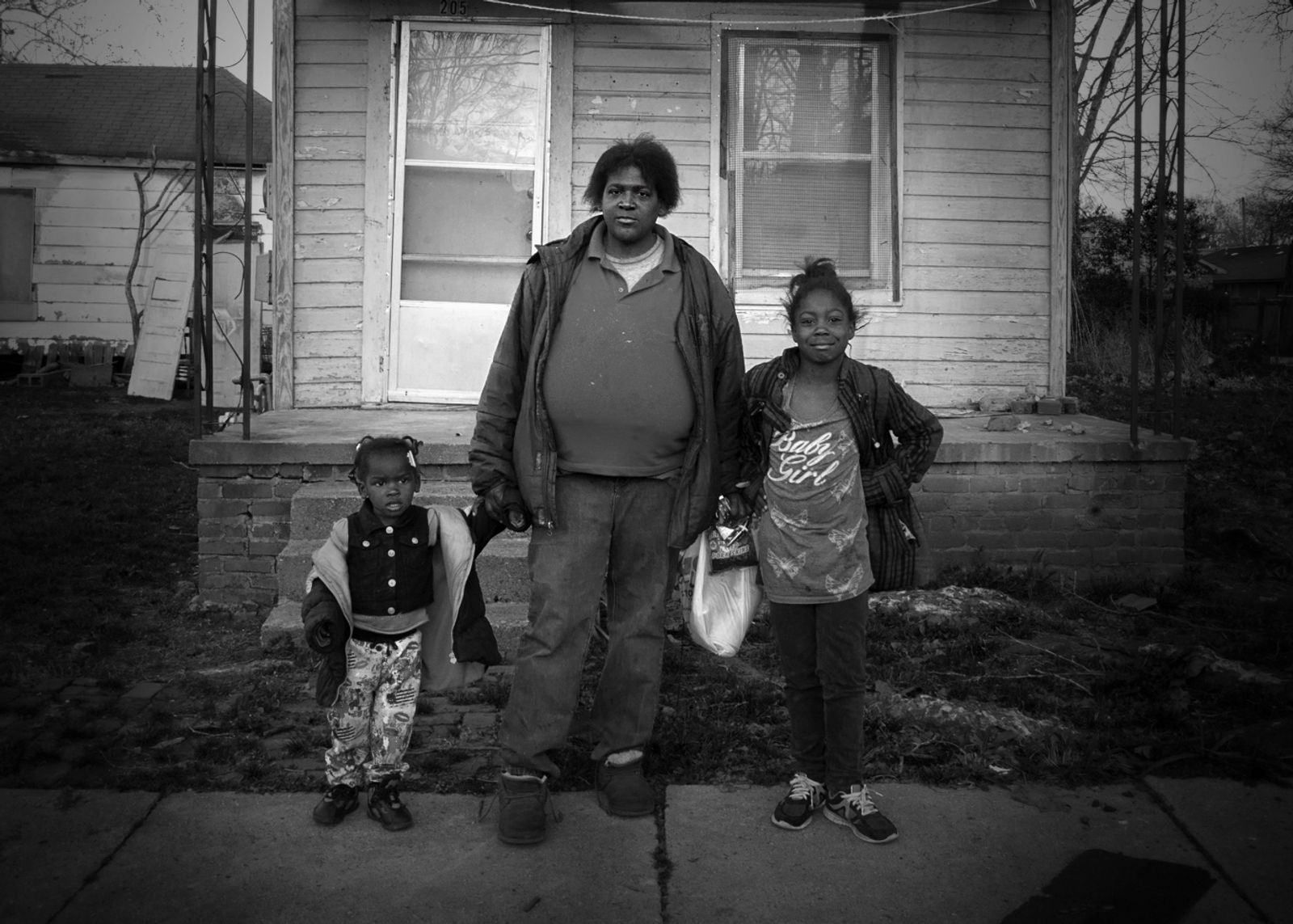 © Rebecca Moseman - Family. A mother and her two daughters pause outside of an abandoned home on the streets of Greenwood, Mississippi.