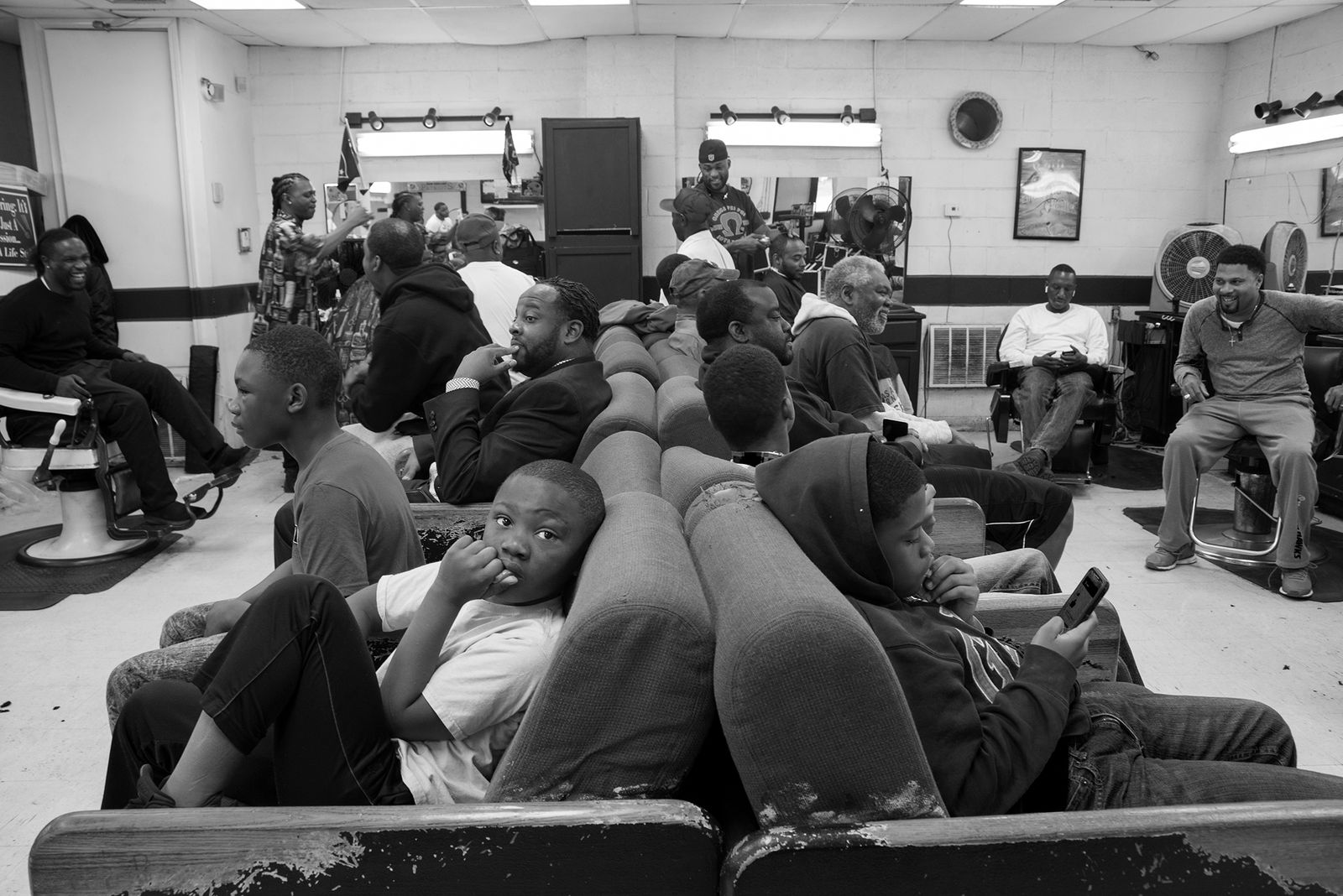 © Rebecca Moseman - Barbershop Crowd. A scene from a crowded local barbershop within the city of Clarksdale, Mississippi.