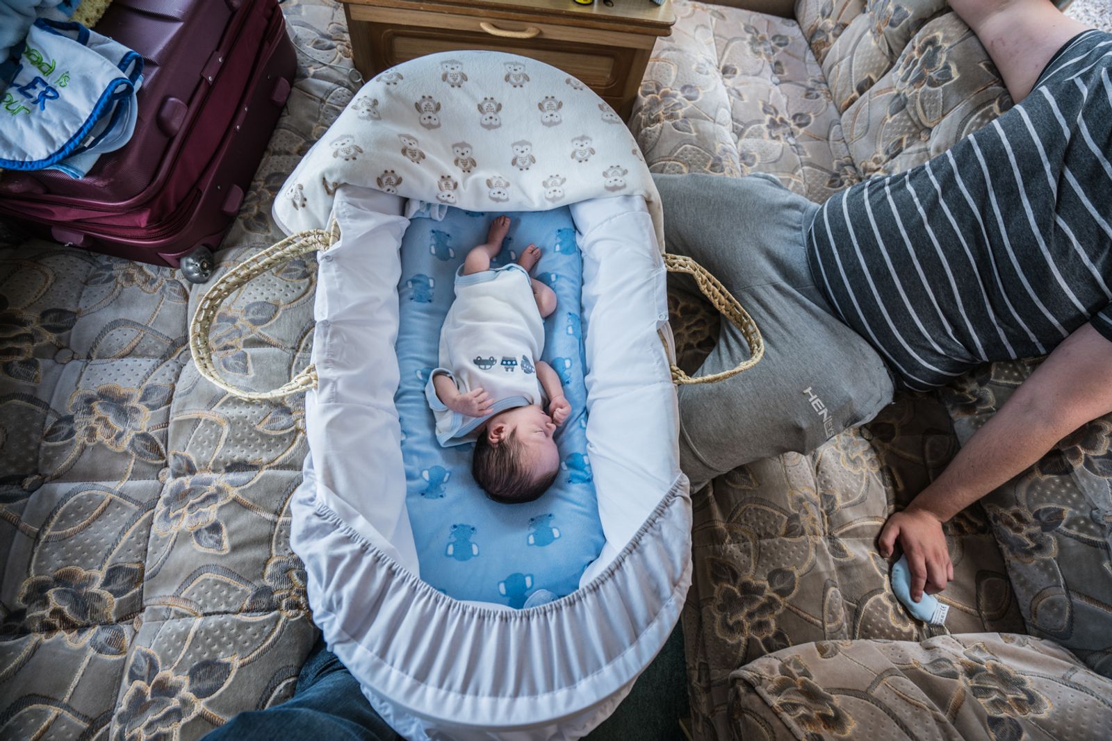 © Stephen Gerard Kelly - John (24) looks at his newborn baby son in his caravan.