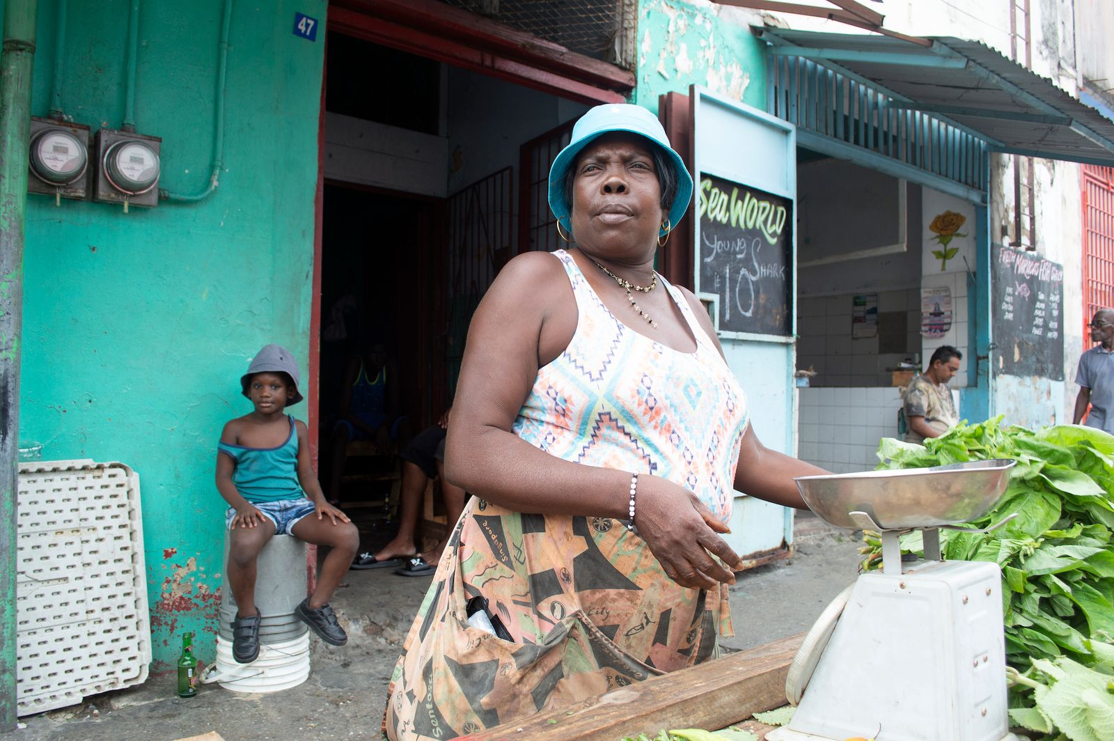© Johanne Rahaman - A vegetable and fish vendor at the George Street Market - her granddaughter in the background.Port of Spain, Trinidad 2015