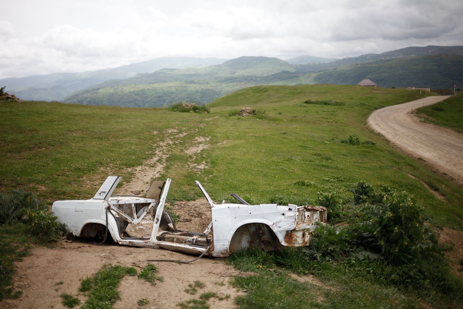 © EDUARD KORNIYENKO - A view on the remains of body shell of Lada car near the road in the mountains of Dagestan.