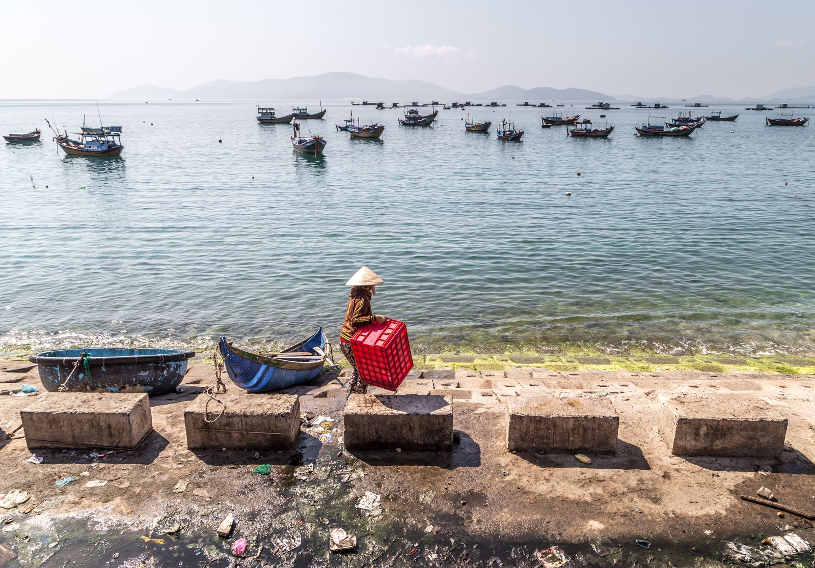 © Nikolay Epifanov - Red Box. A woman throws fish waste back into the water. Nha-Trang, Vietnam, 2017.