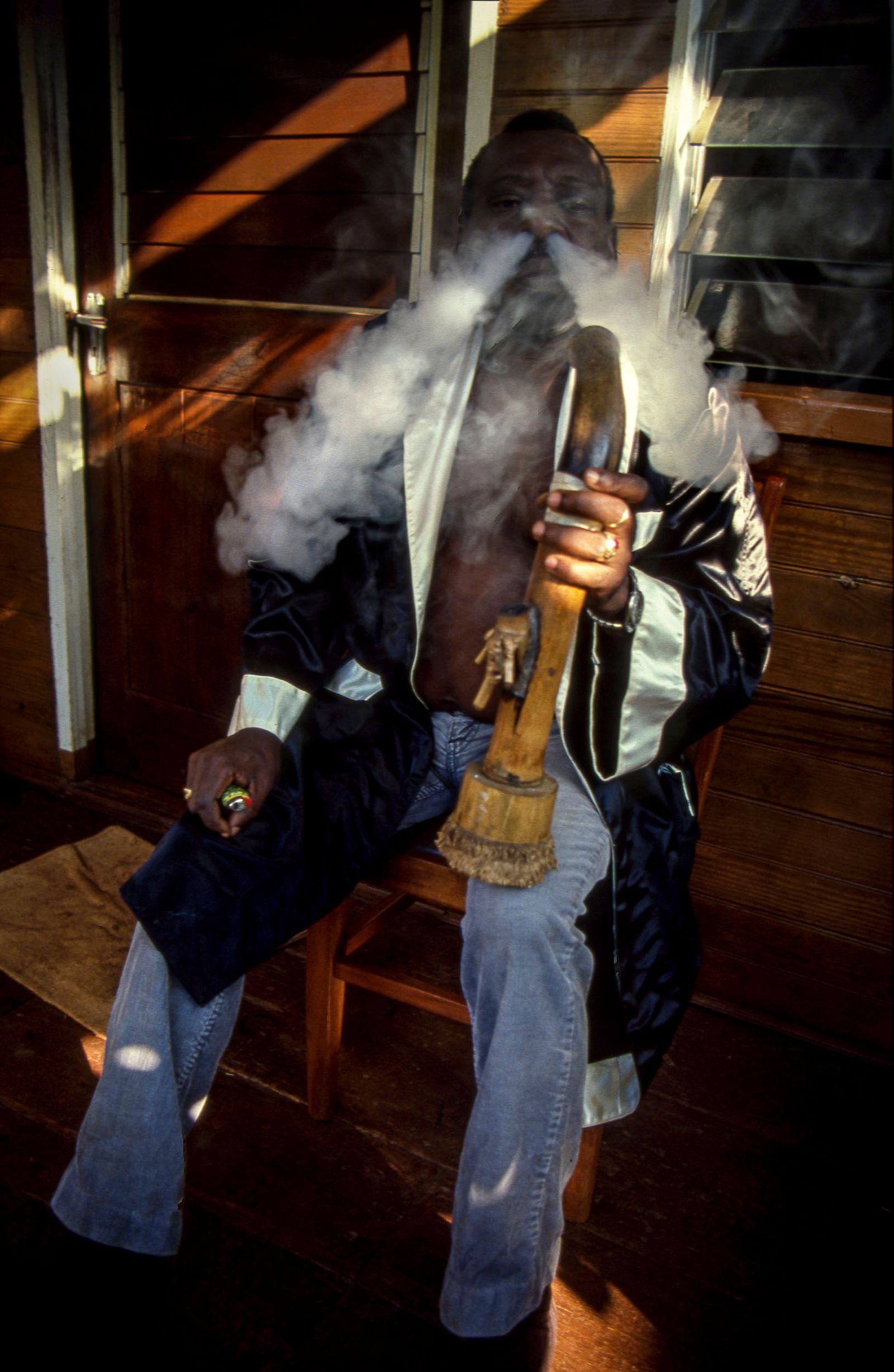 © Steven Edson - Jamaican man deeply exhaling cannabis from a bong. Negril, Jamaica