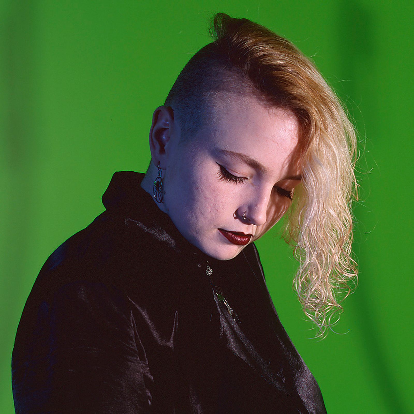 © Steven Edson - Portrait of Goth woman with partially shaved head looking away from camera.