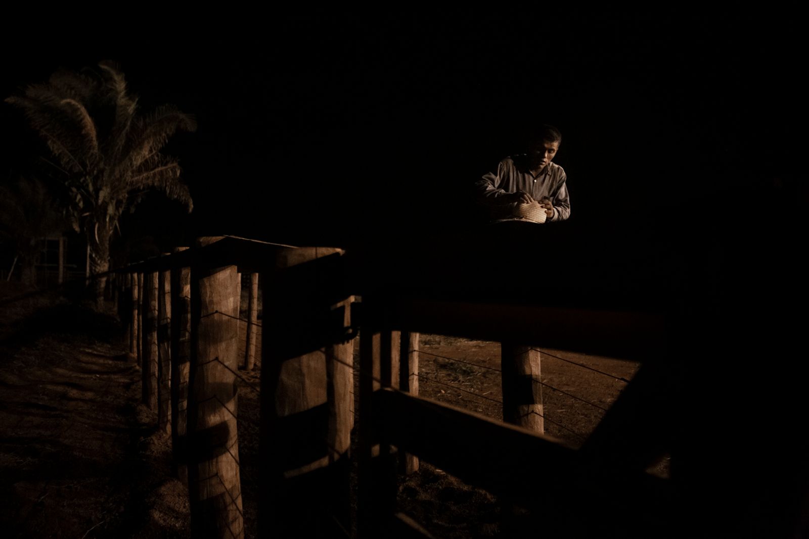 © Carolina Arantes - A cowboy sat in a fence, arranging his hat. Pontes e Lacerda, Mato Grosso, Brazil, 2015.