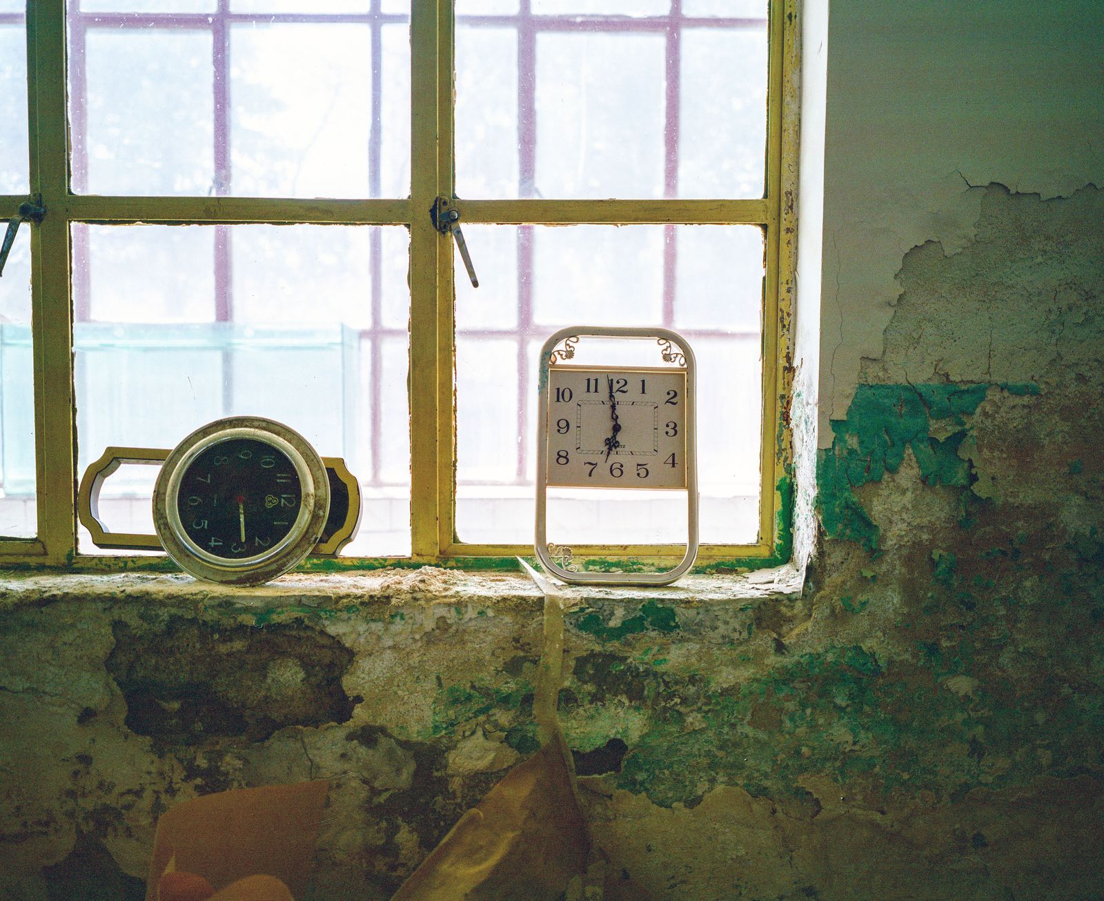 © Pan Wang - April 14, 2018，Yumen City, Gansu Province, China. In an abandoned house, two wall clocks are placed on the window sill.