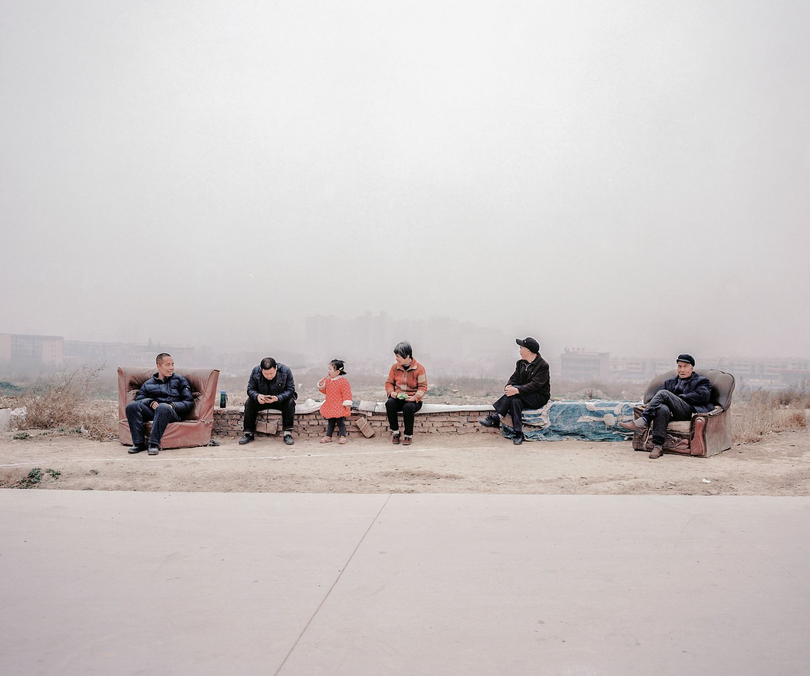 © Pan Wang - 06.Farmers sit in front of a strip of expropriated land behind them that was once an orchard