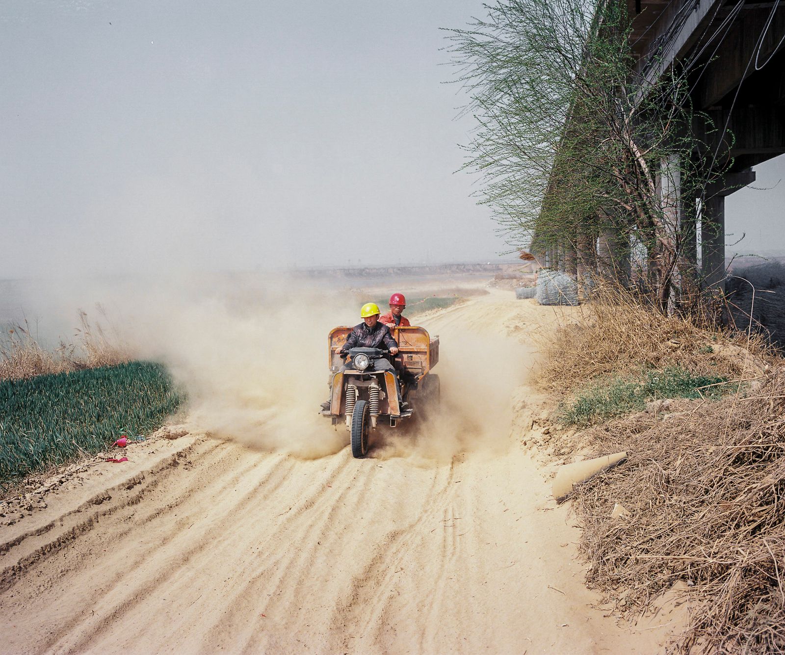 © Pan Wang - 12. The workers who reinforced the bridge drove three wheeled motorcycles to lift up the vast yellow soil in the sky