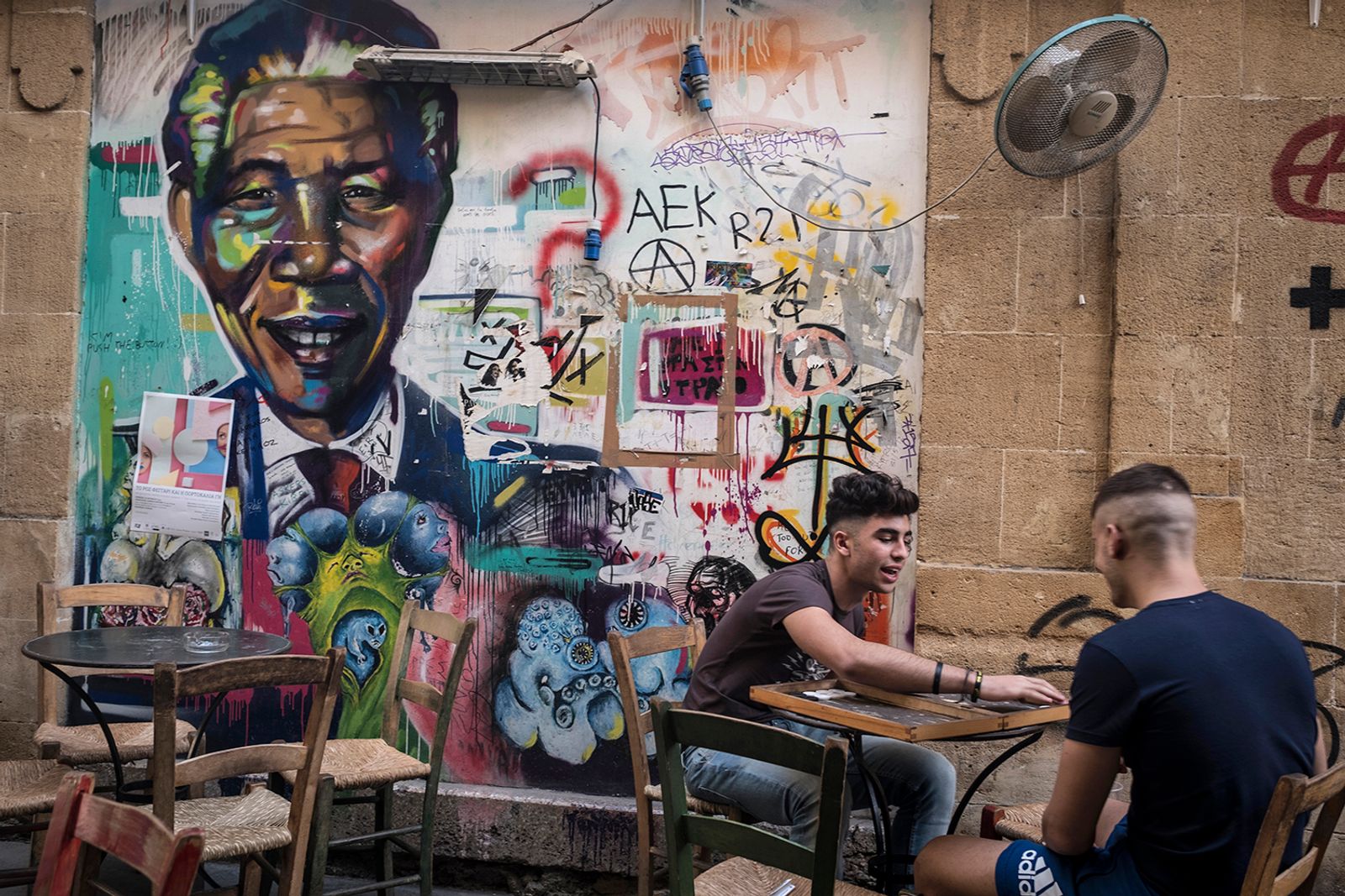 © Sahan Nuhoglu - Two Cypriot youngsters are playing black gammon in front of a Mandela mural in the city of Nicosia, Cyprus.