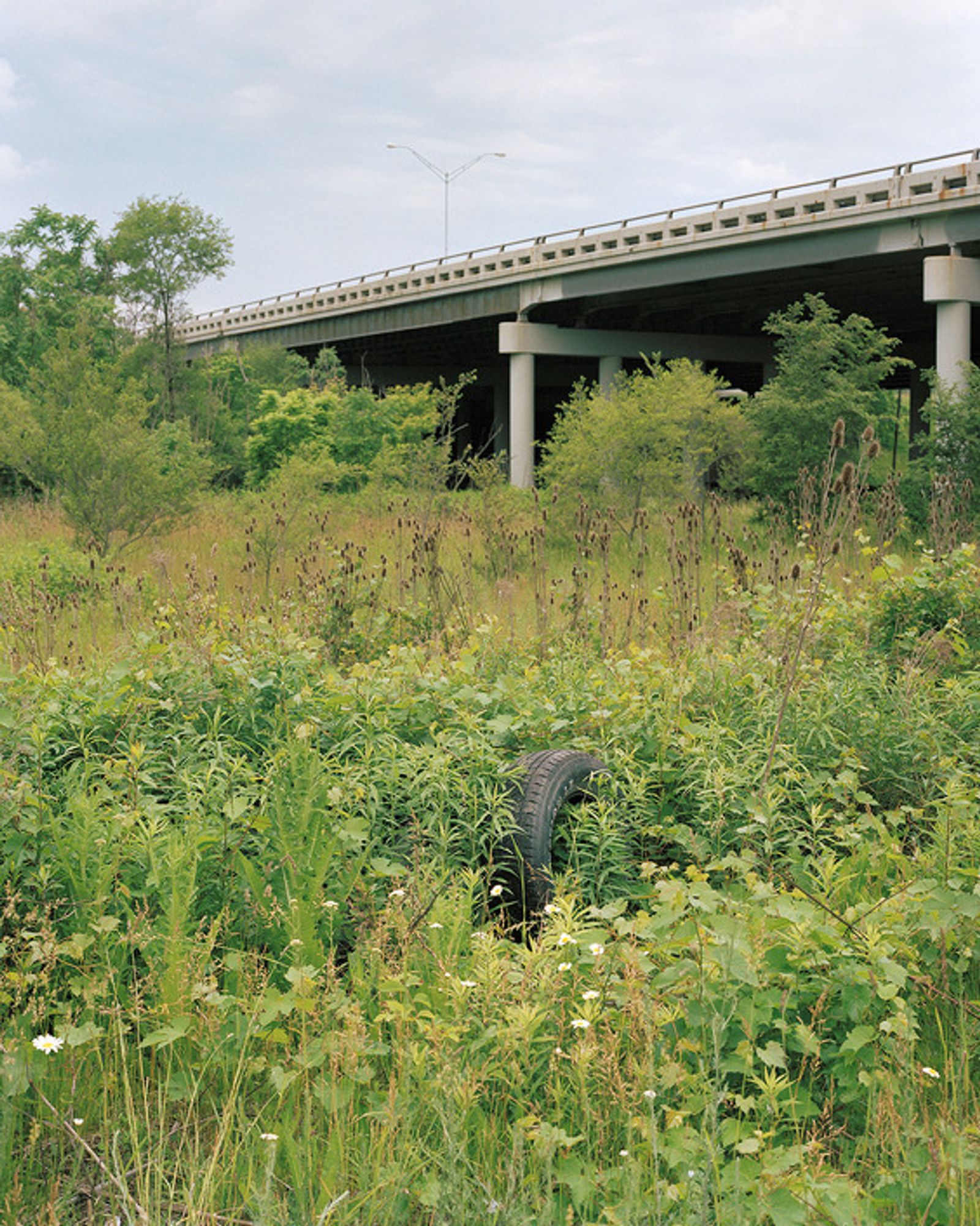 © Juan Madrid - A tire lays in a field on the south side near an Interstate 69 overpass.