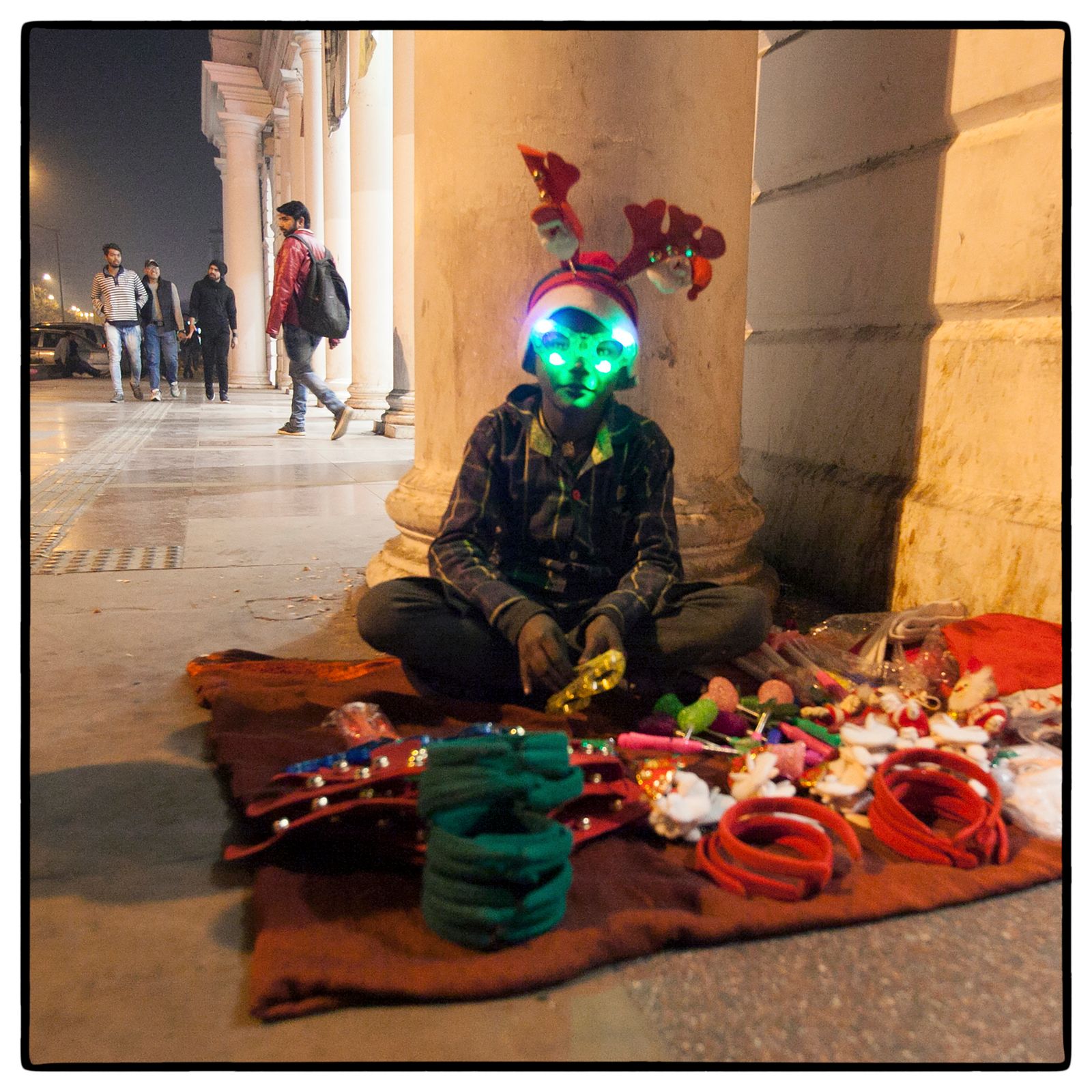 © Vijay S. Jodha - Teenager wears a light mask – one of the many inexpensive items he is selling off the pavement.