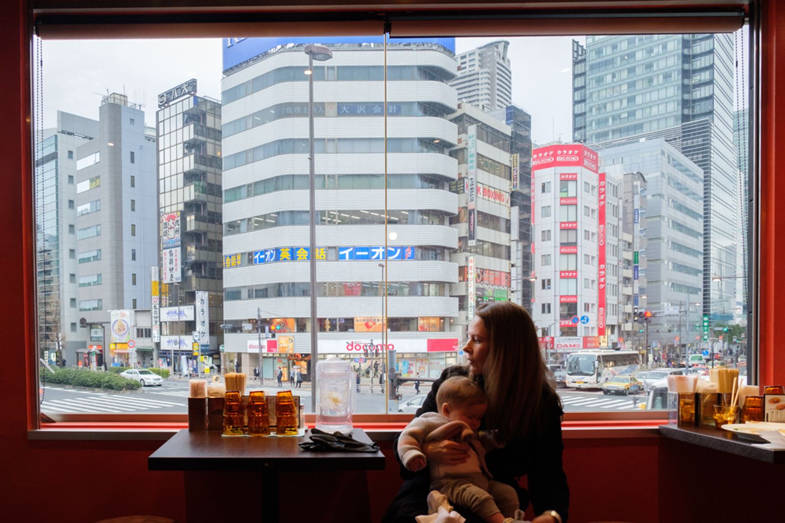 © Vincent Dupont-Blackshaw - Lunch with a view: A traveller takes a break with her baby in a noodle fast food restaurant. (Tokyo, Japan)