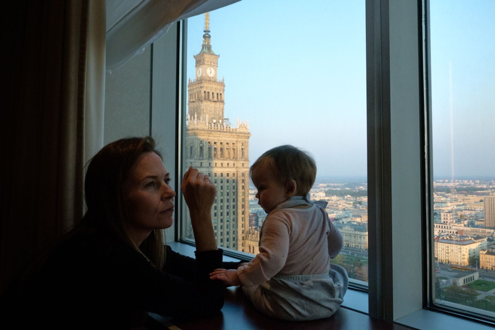 © Vincent Dupont-Blackshaw - Seated on top: A traveller overlook Warsaw from her hotel room. (Warsaw, Poland)