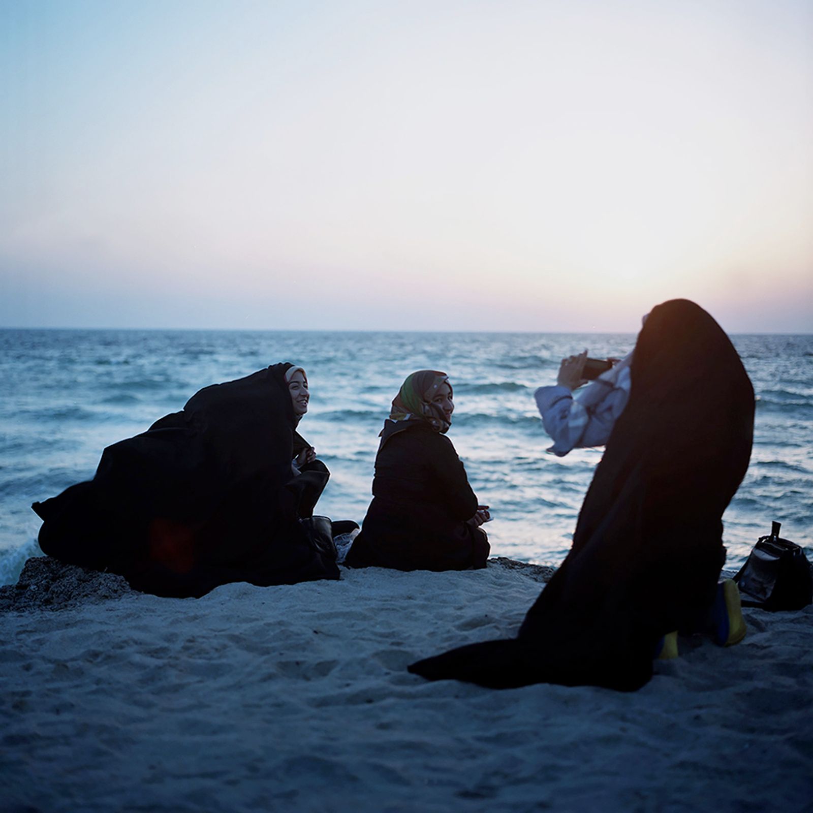 © Loulou d’Aki - Down by the water, Iranian girls in chador take pictures of each other at sunset on Kish island.