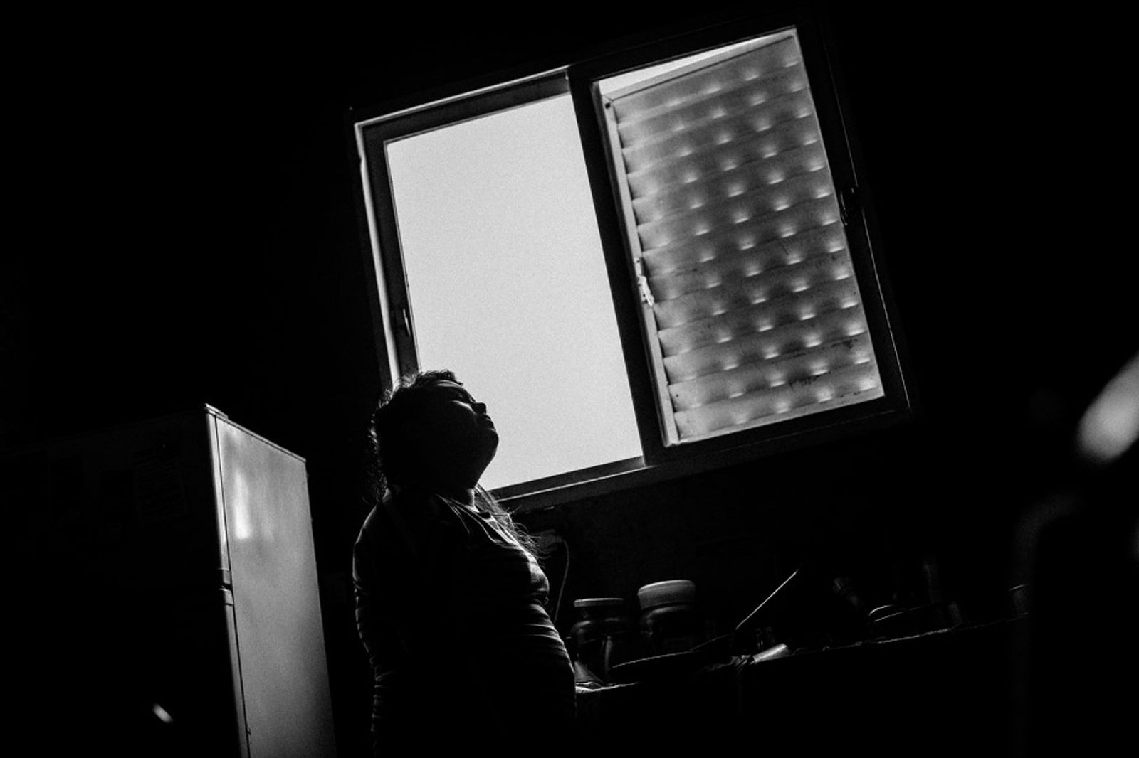 © Sarah Pabst - Stefi takes a break while cooking and let's the sun comfort her face in Monte Chingolo, Lanús, Province of Buenos Aires.