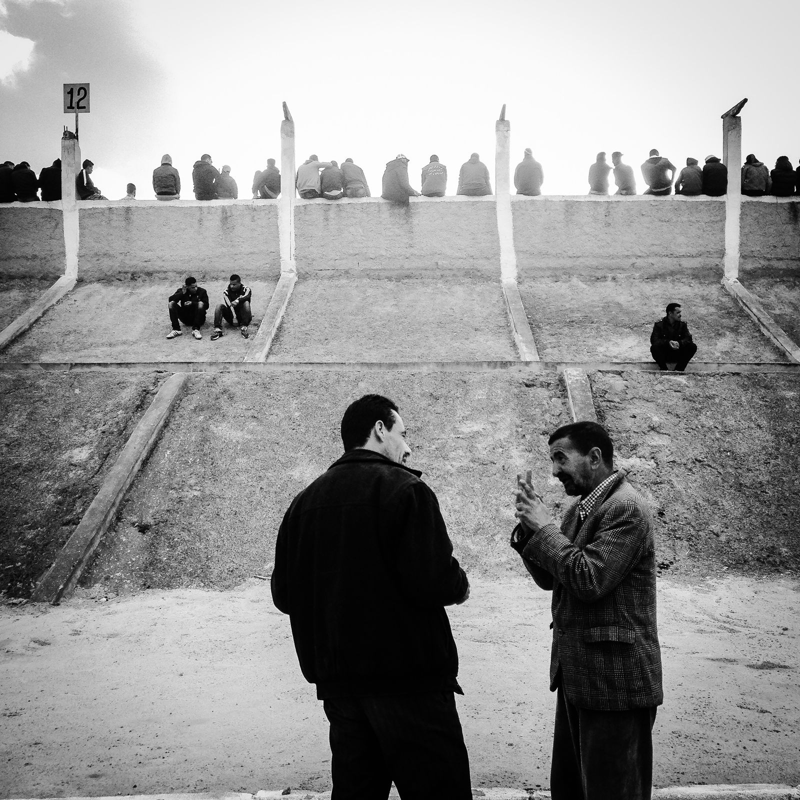 © Fethi Sahraoui - Two men discussing in a stadium.