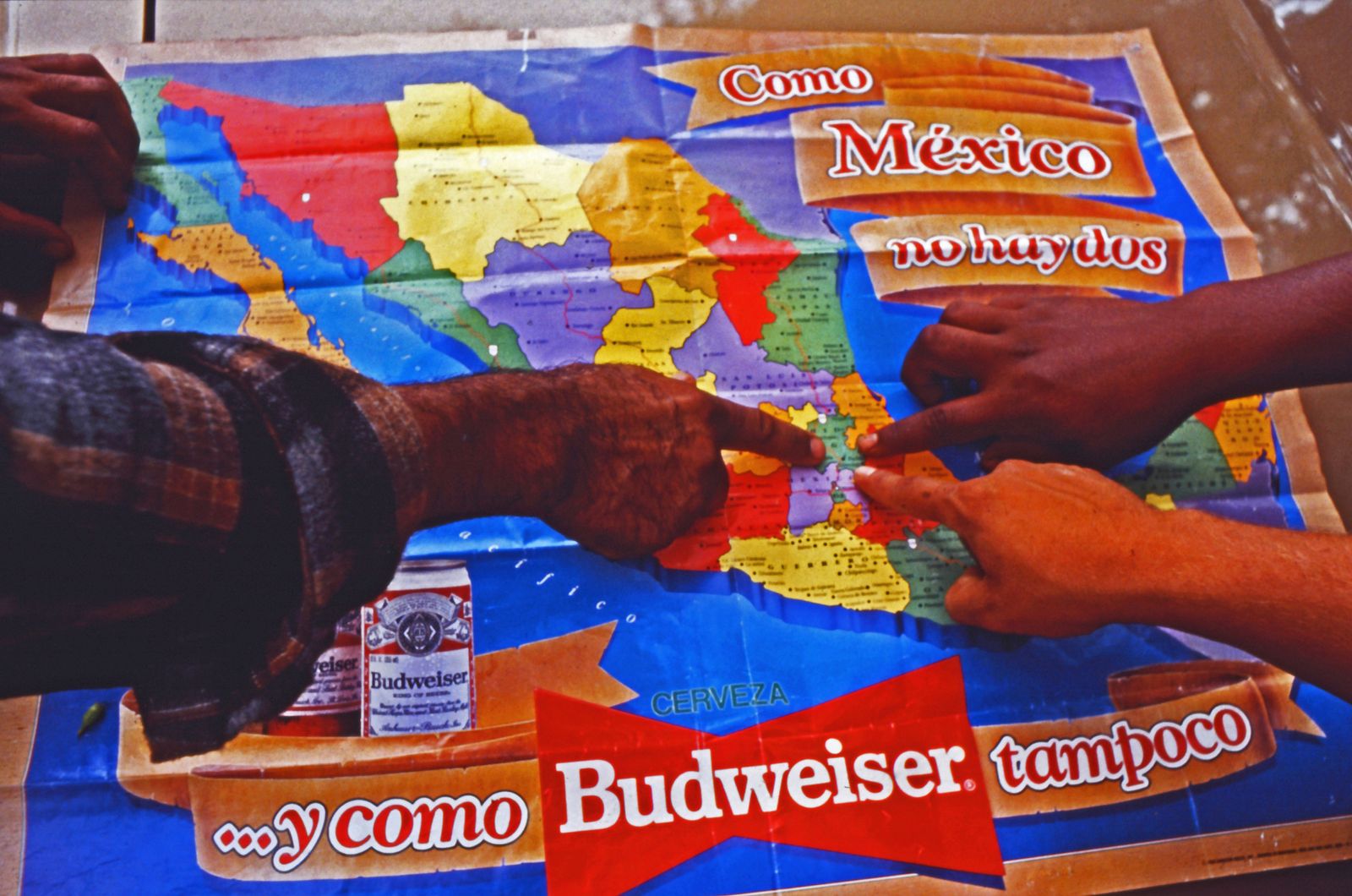 © Richard Street - Huron farmworkers point to their home town on a Budweiser beer map spread on the trunk of their automobile.