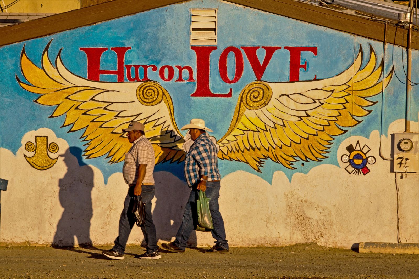 © Richard Street - Farmworkers returning from the fields pass in front of a mural beside the Mexico cafe.