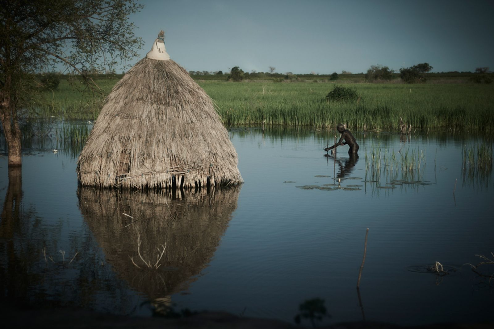© Christina Simons - A man wades with a net to catch fish in the floodwaters around Bentiu.