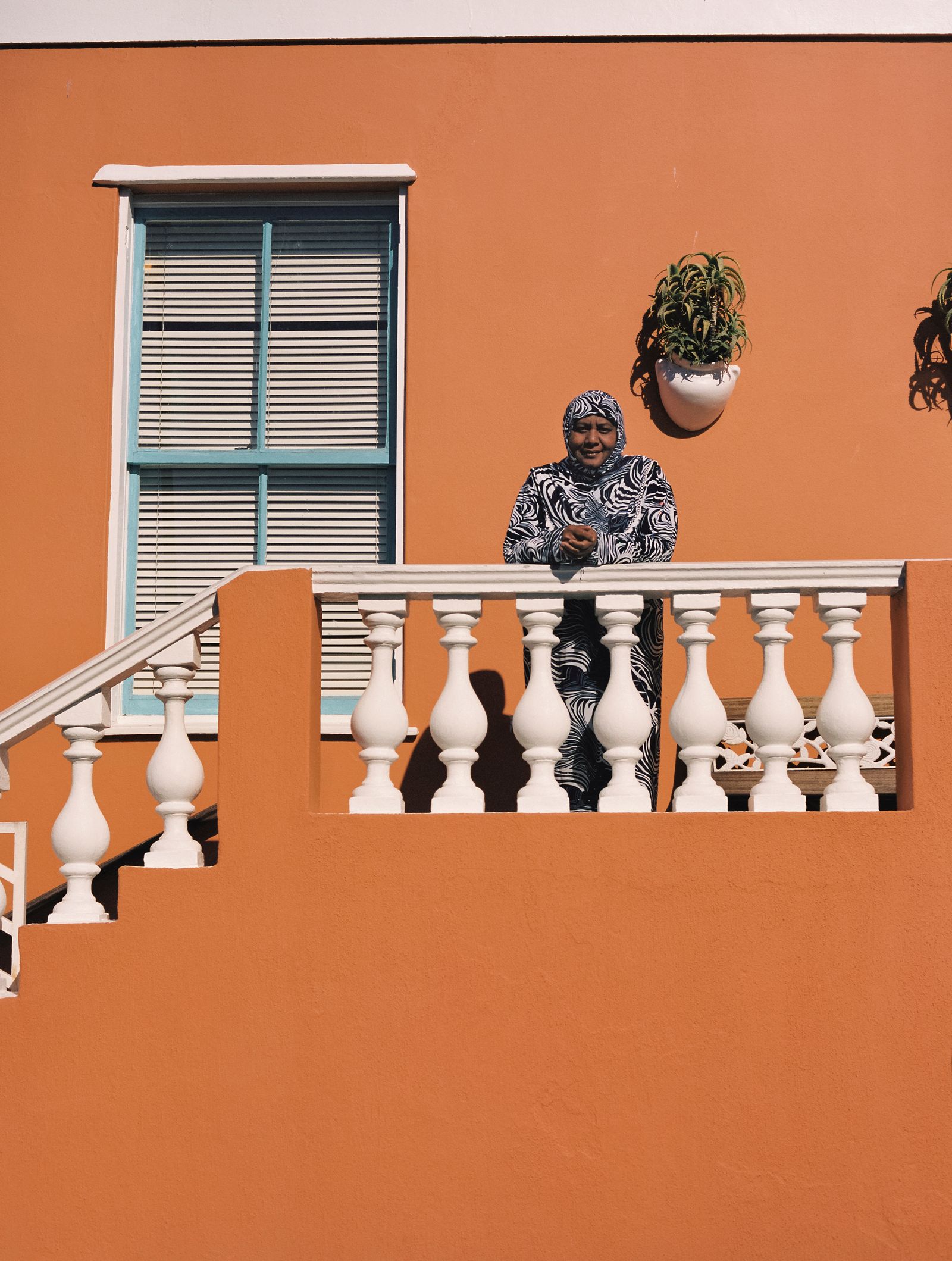 © Ayesha Kazim - Rashieda, a long-time resident of Bo Kaap, stands for a portrait from her balcony on Wale Street.