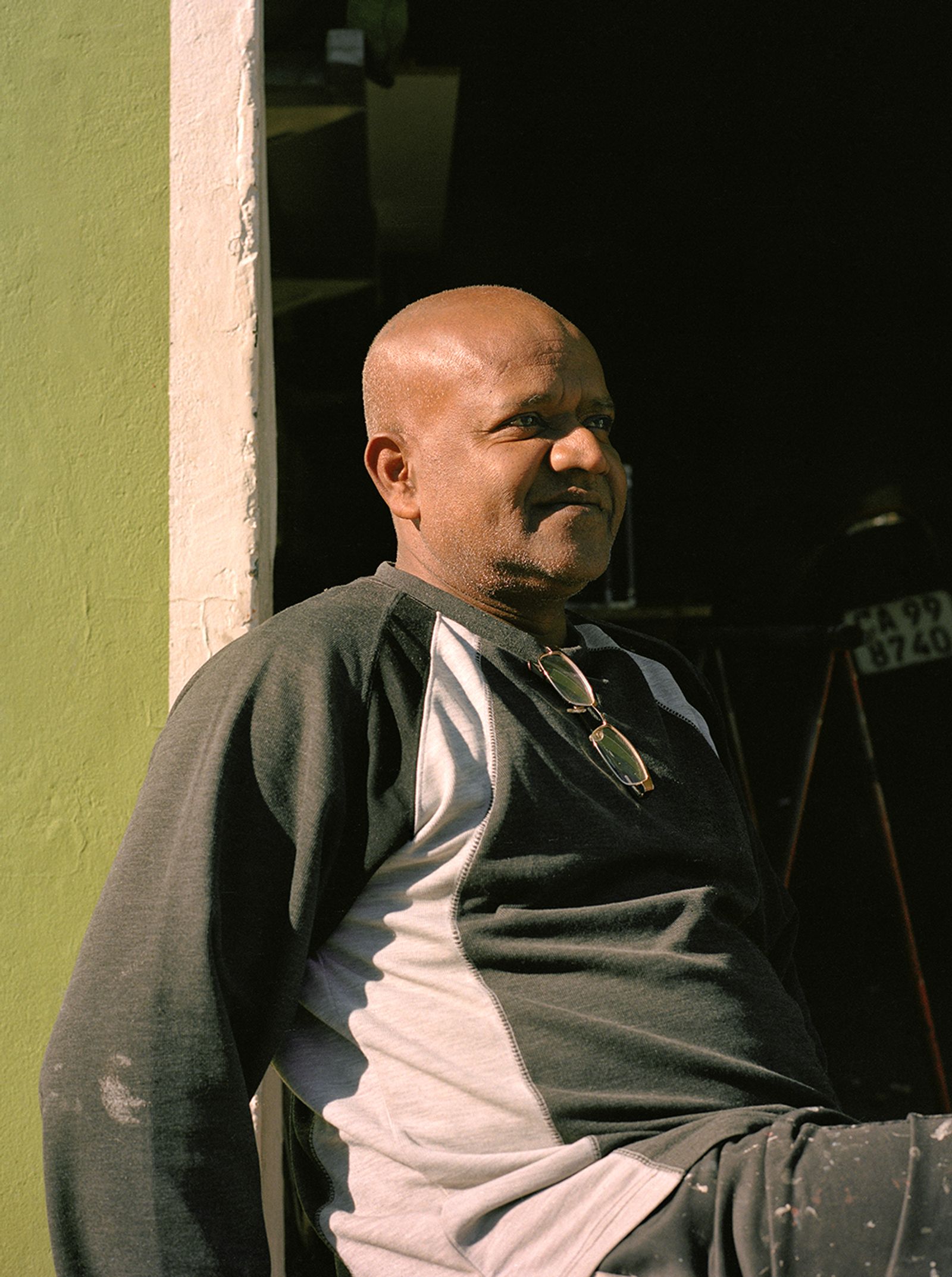 © Ayesha Kazim - A man sits for a portrait outside of his garage on Van Der Meulen Street.