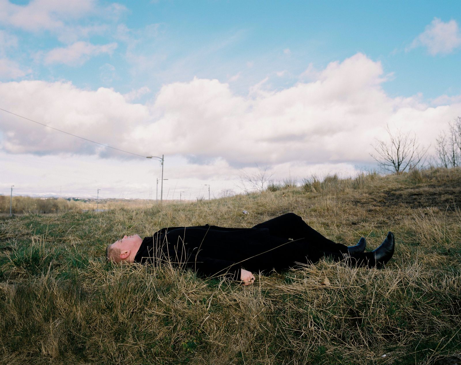© Kirsty Mackay - Billy age 19 lies on the ground where council housing once stood, Easterhouse.