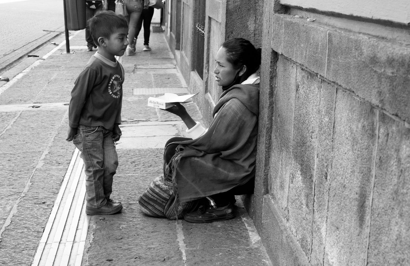 © Roxanne Munson - A woman selling candy on the street talking to a little boy.