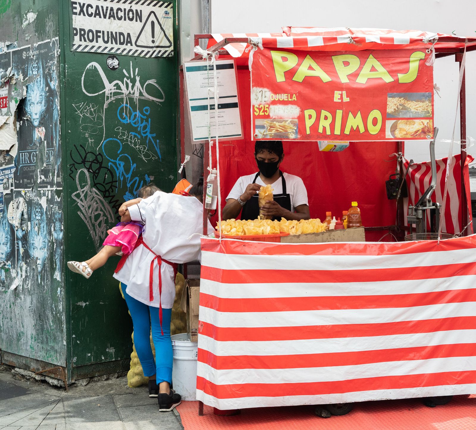 © Roxanne Munson - A man preparing chips while a woman is holding a little girl.