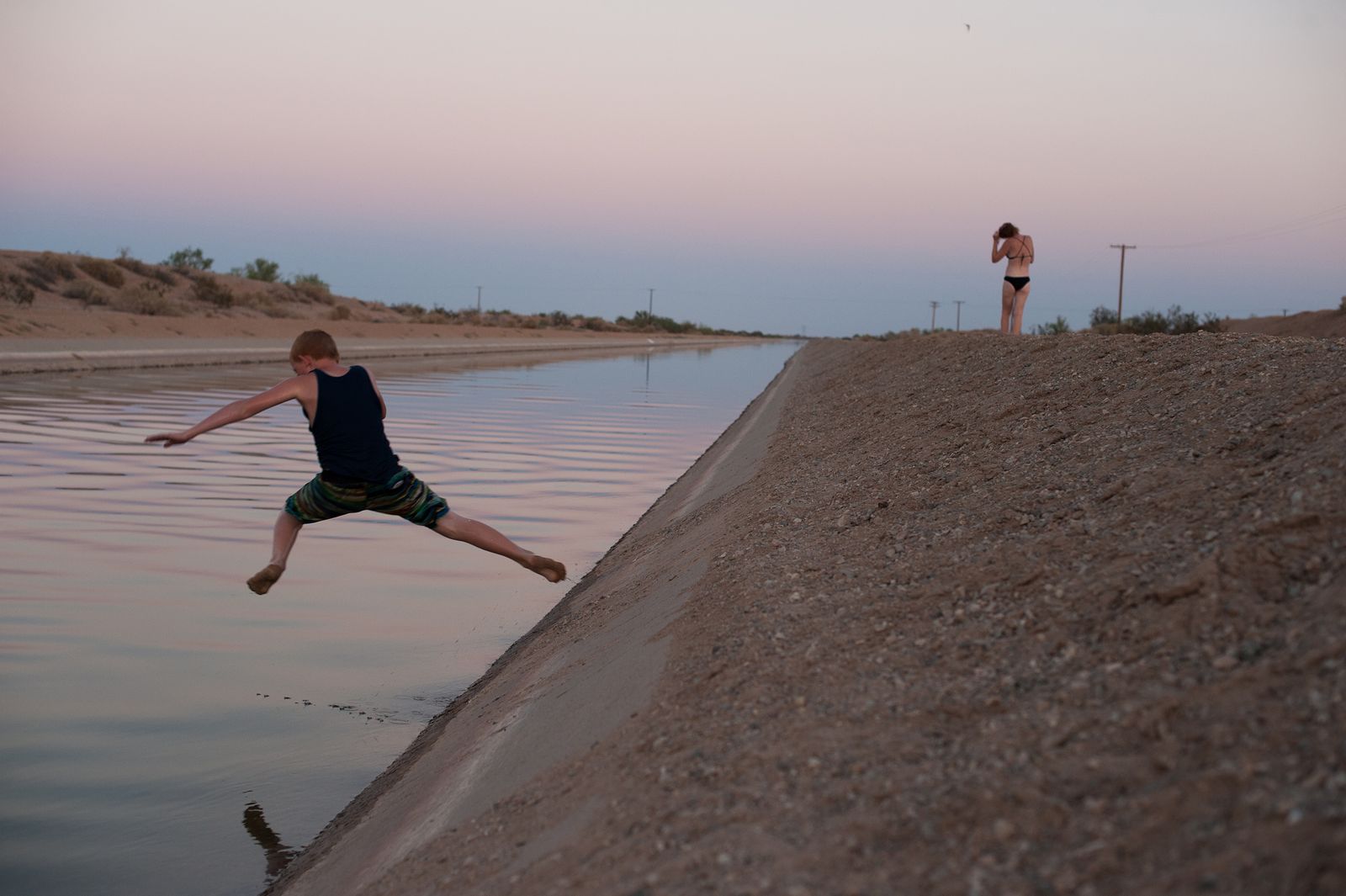 © Jason Houge - Families risk arrest and drowning in swift currents to swim in the cool waters of a nearby canal; Slab City, USA 2018