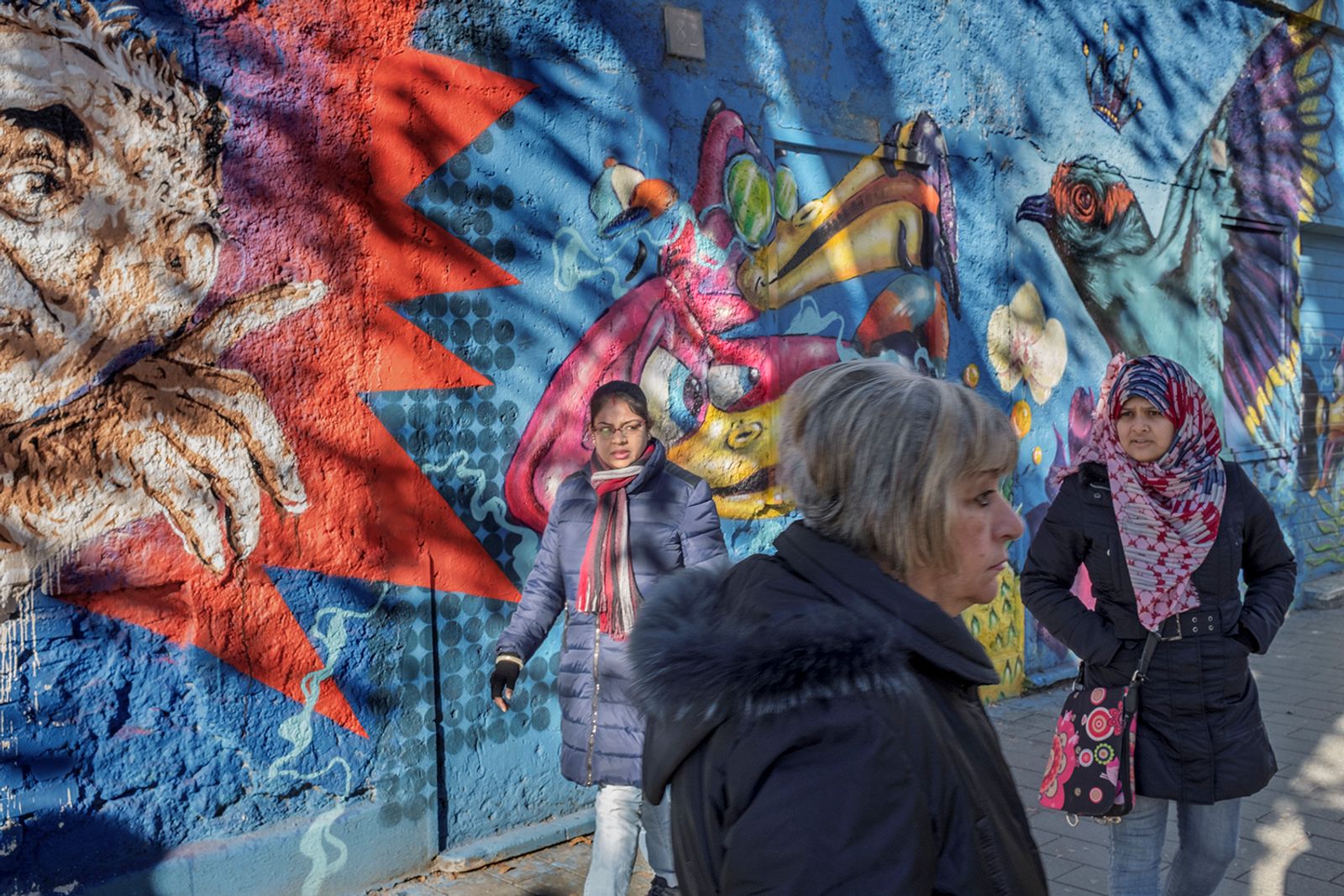 © Paolo Patrizi - A street scene bathed in winter sunlight. Women walk past a mural on Via di Torpignattara, in the eastern periphery of Rome.