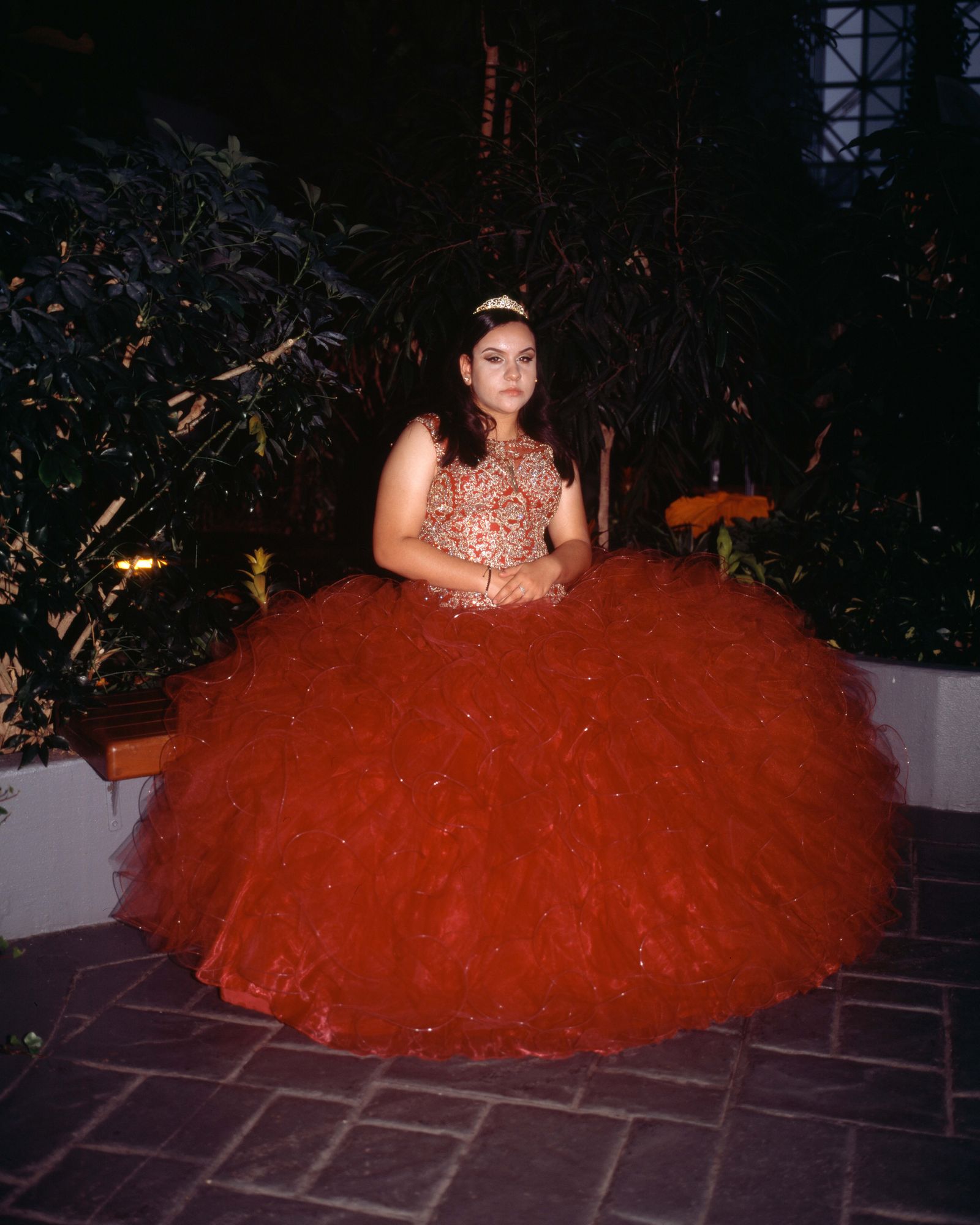 © Samantha Cabrera Friend - Quinceañera in an "untraditional" dress poses beside an indoor garden.