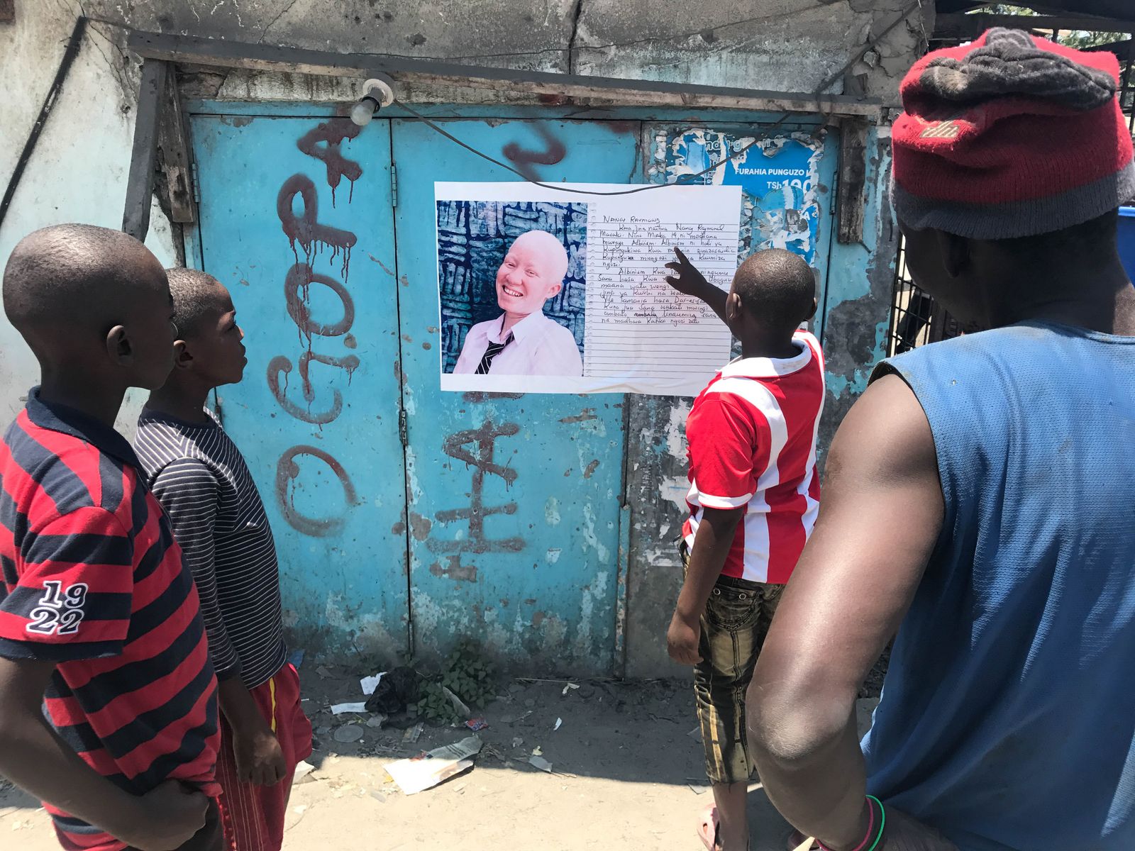 © Soraya Matos - *Locals gather outside a market stand to read albinism stories. – Kariakoo, Dar es Salaam, Tanzania.